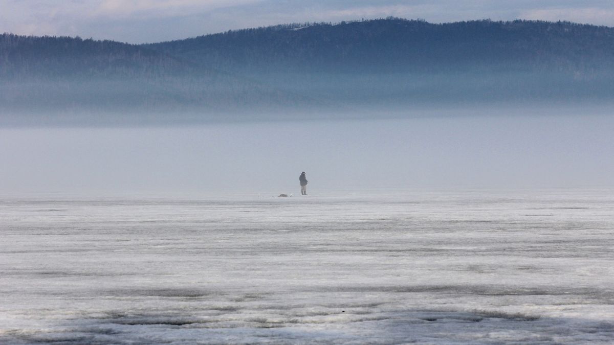 Ice angler standing in the distance on a frozen lake