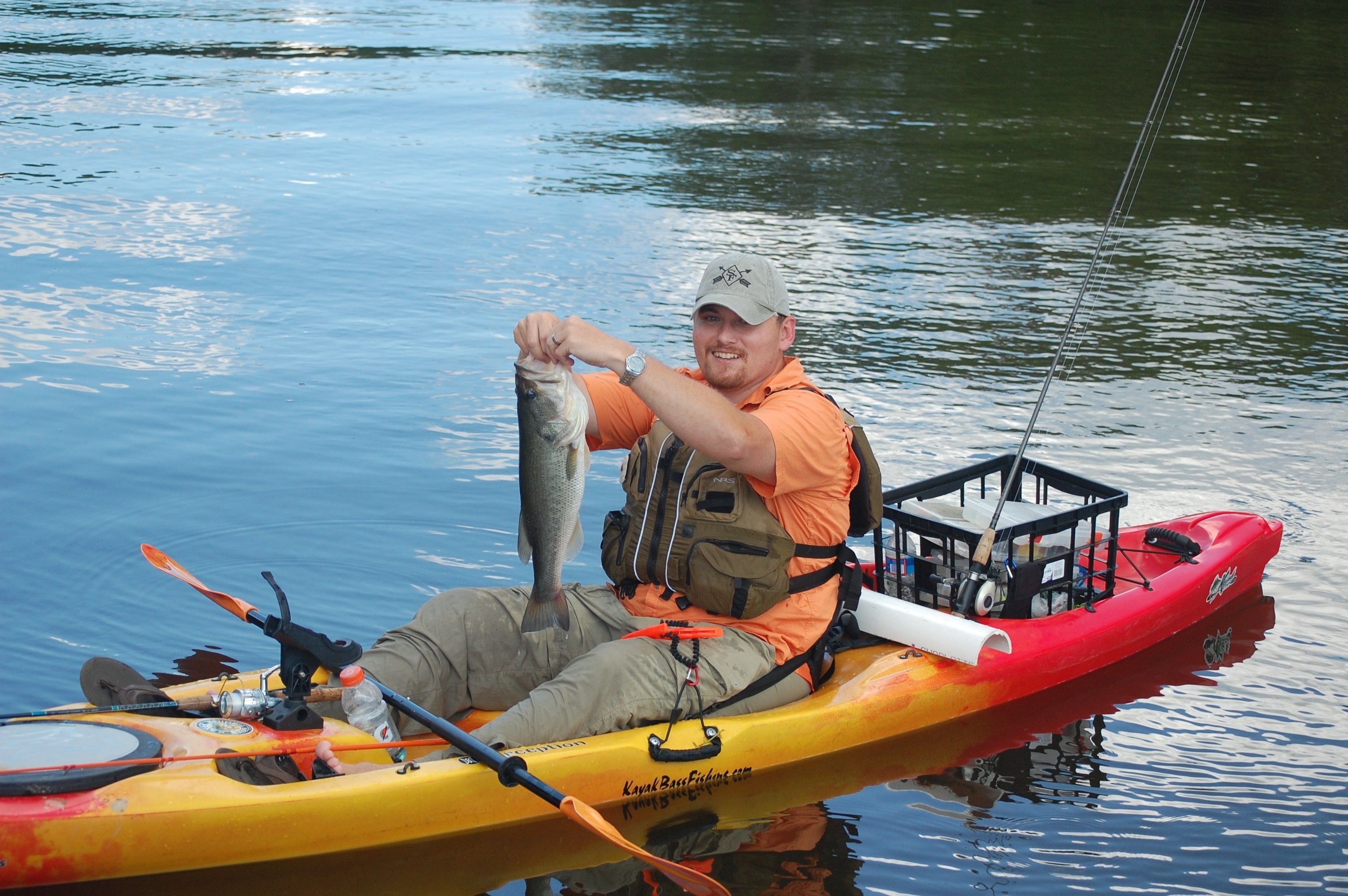 Fisherman in a kayak holding a largemouth bass.