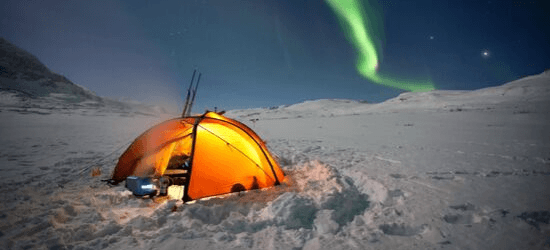 Orange glow coming from a round tent. Snow and northern lights and moonlight.