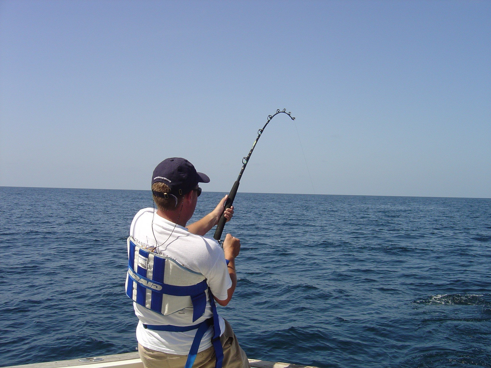 Man fishing with an offshore fishing rod wearing a fighting belt.