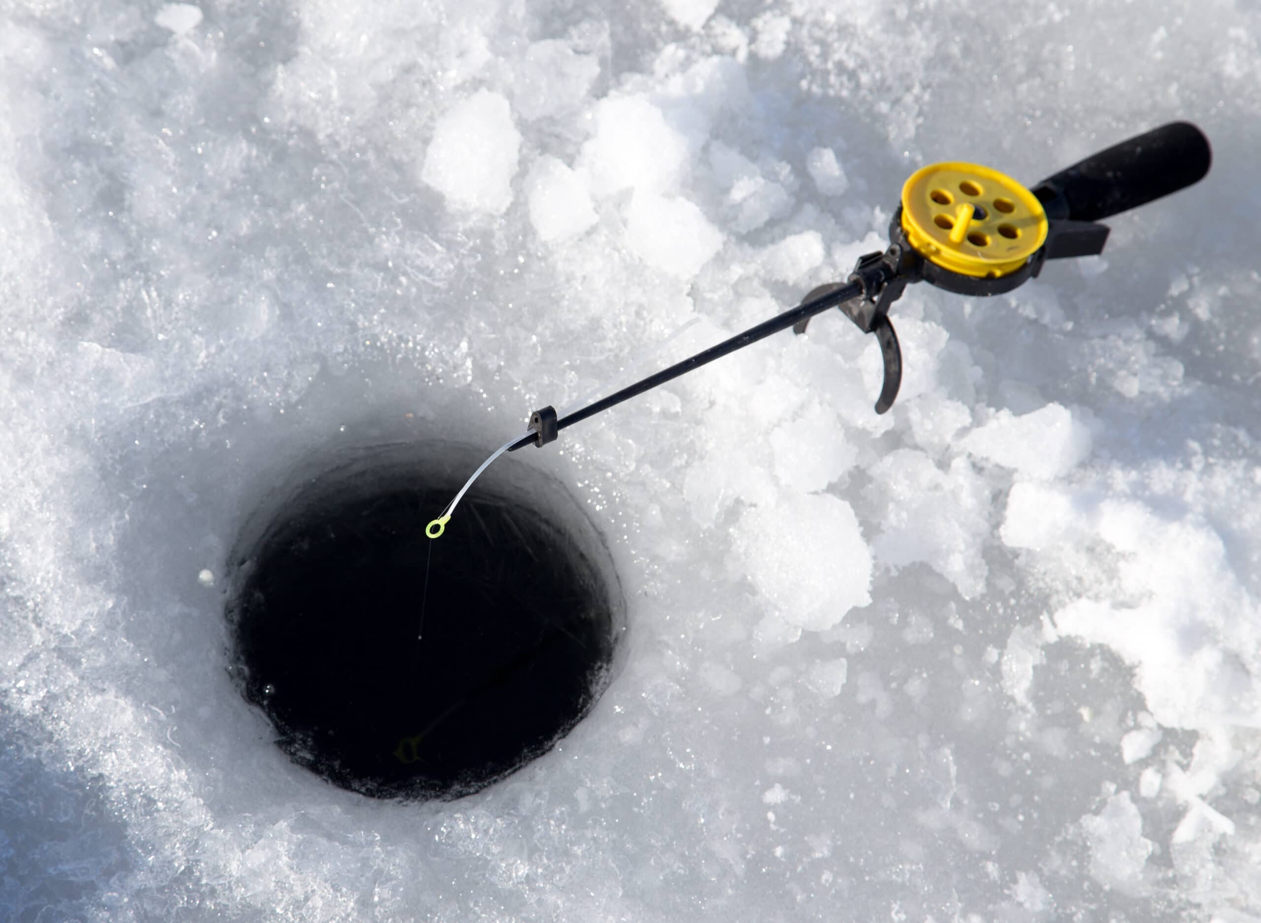 Ice fishing rod over an open ice hole.