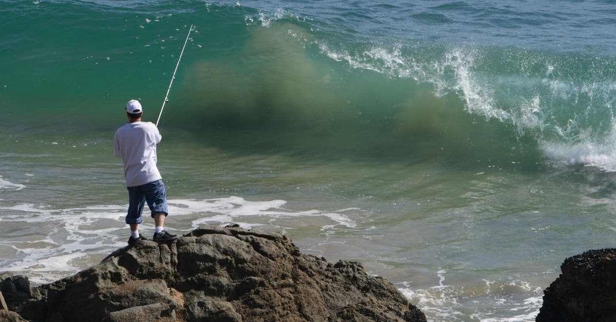 Man Fishing From Rocks in an Ocean.